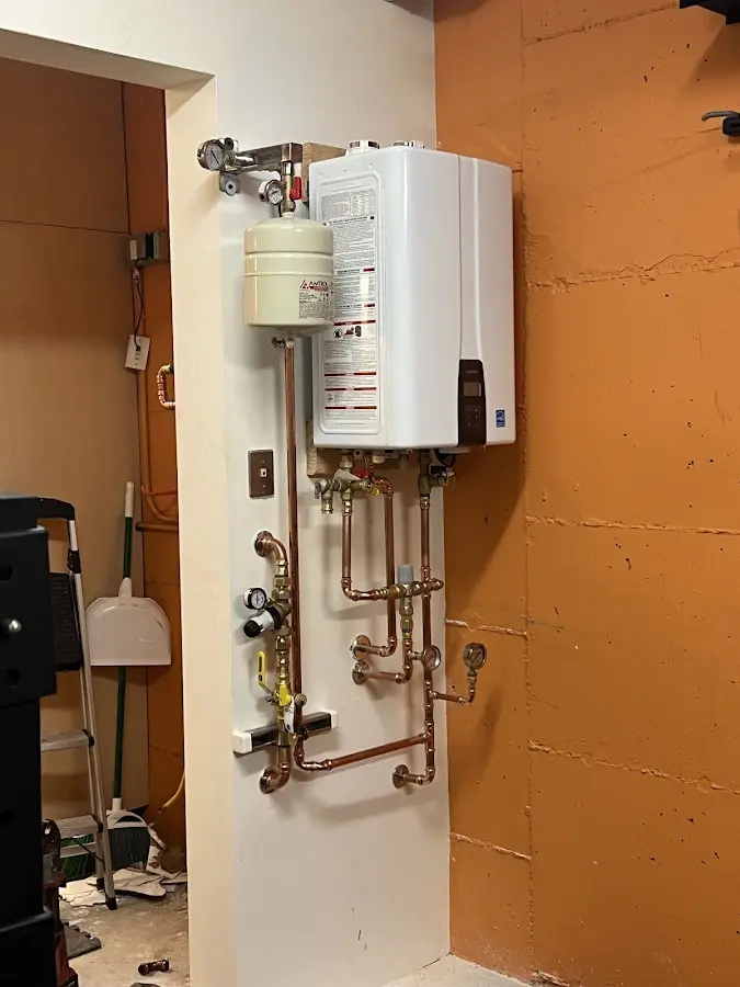 Plumbing technician inspecting water heater connections in Stamford